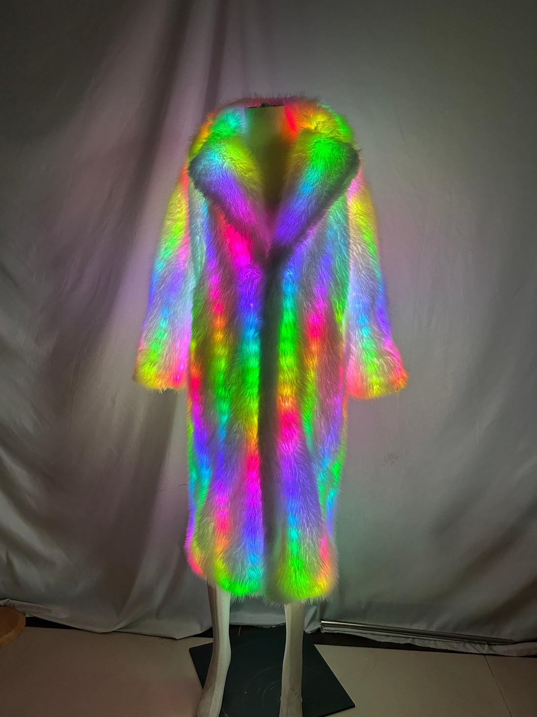 Woman's white LED faux fur long coat glowing in rainbow colors on a mannequin, front view